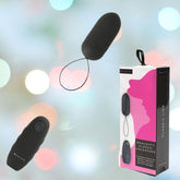 A stylish black bullet vibrator, complete with a remote control, is highlighted against a blurred background. The packaging, tastefully designed in pink and white hues, prominently features the name "B Swish Bnaughty Classic Unleashed - Black," ideal for external stimulation.